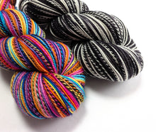 Load image into Gallery viewer, Two skeins of yarn on a white background: one multicolor with bright pink, orange, yellow, blue, and purple stripes, and one black and white variegated stripe yarn.
