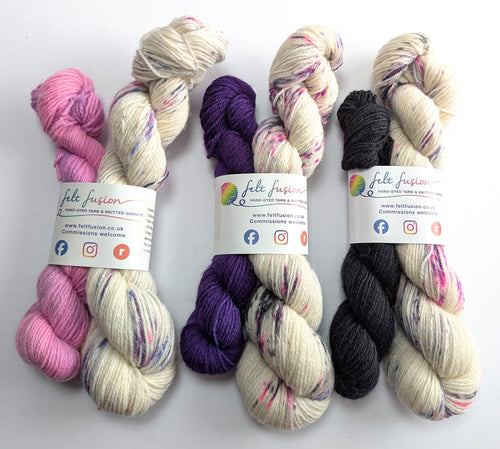 Three sets of yarn in pink, purple, and black with visible branding on a white background