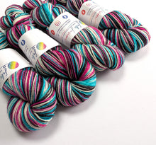 Load image into Gallery viewer, Four skeins of variegated yarn with white paper labels, featuring stripes of pink, teal, black, and cream, arranged on a plain white background.
