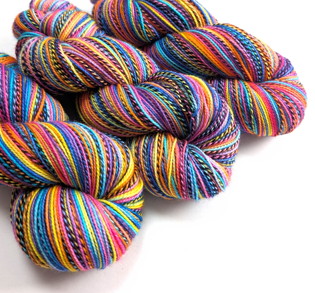 Pink, purple, yellow, orange and blue skeins of yarn.
