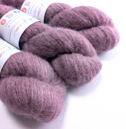 Three skeins of purple yarn with labels on a white background