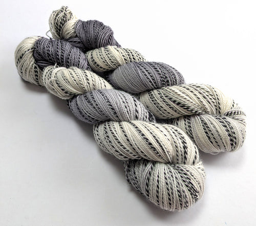 Two skeins of grey and white yarn on a white background
