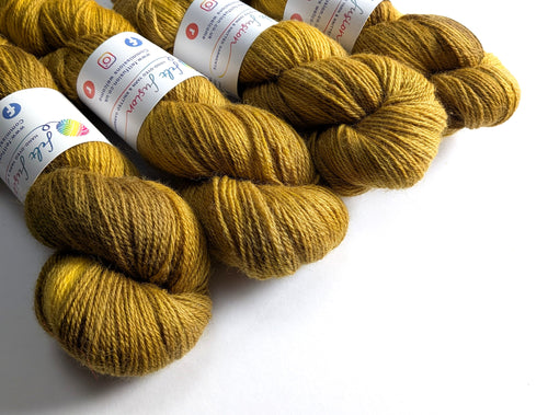 Mustard yellow yarn skeins with labels on a white background