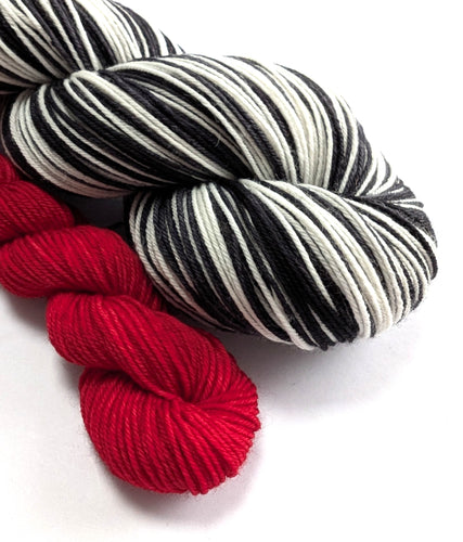 Red, black, and white striped yarn skeins on a white background