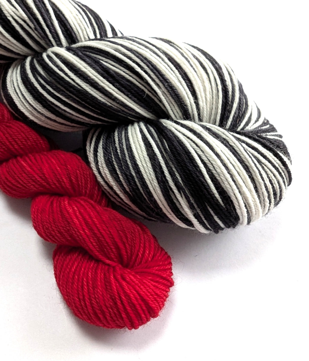 Red, black, and white striped yarn skeins on a white background