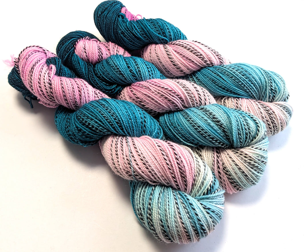 Three skeins of yarn in pink and teal on a white background