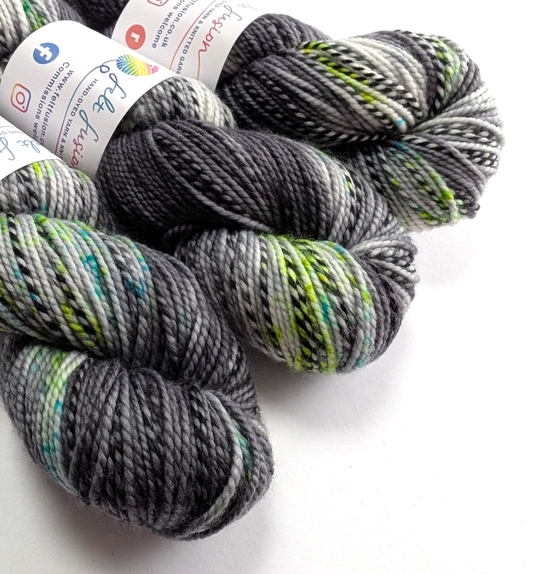 Three skeins of gray and green yarn with labels on a white background