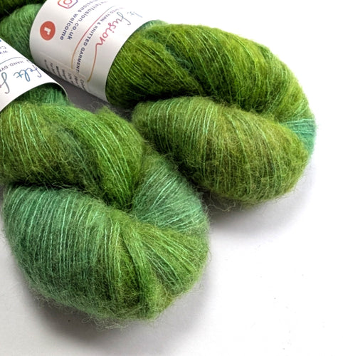 Two skeins of green yarn with a label on a white background