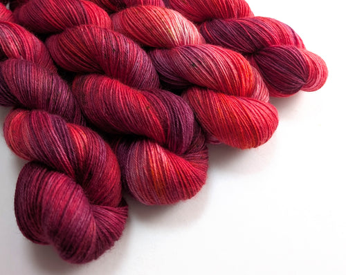 Red and purple skeins of yarn on a white background