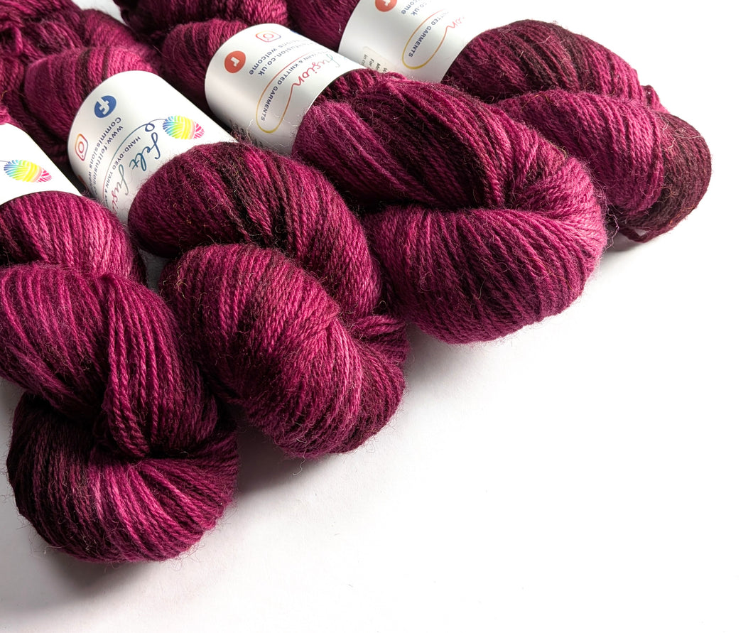 Skeins of deep pink yarn with visible labels on a white background
