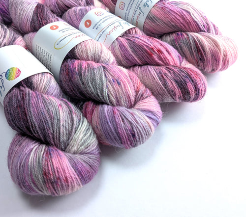 Four skeins of pink yarn with labels on a white background