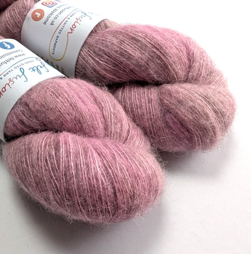 Two skeins of pink yarn with labels on a white background