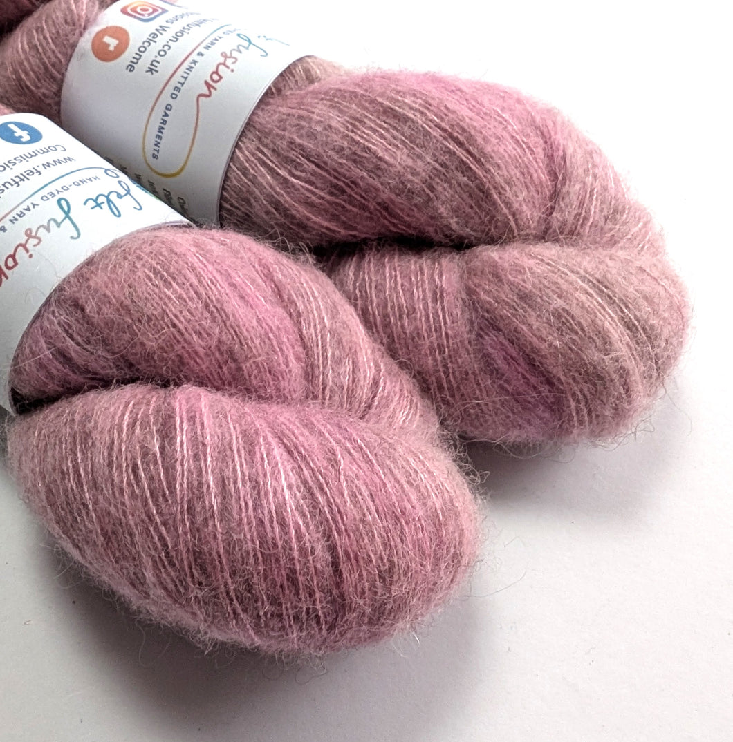Two skeins of pink yarn with labels on a white background