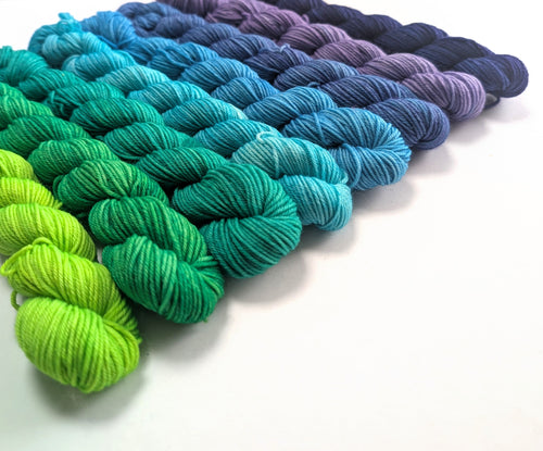 Colorful yarn skeins arranged in a row on a white background
