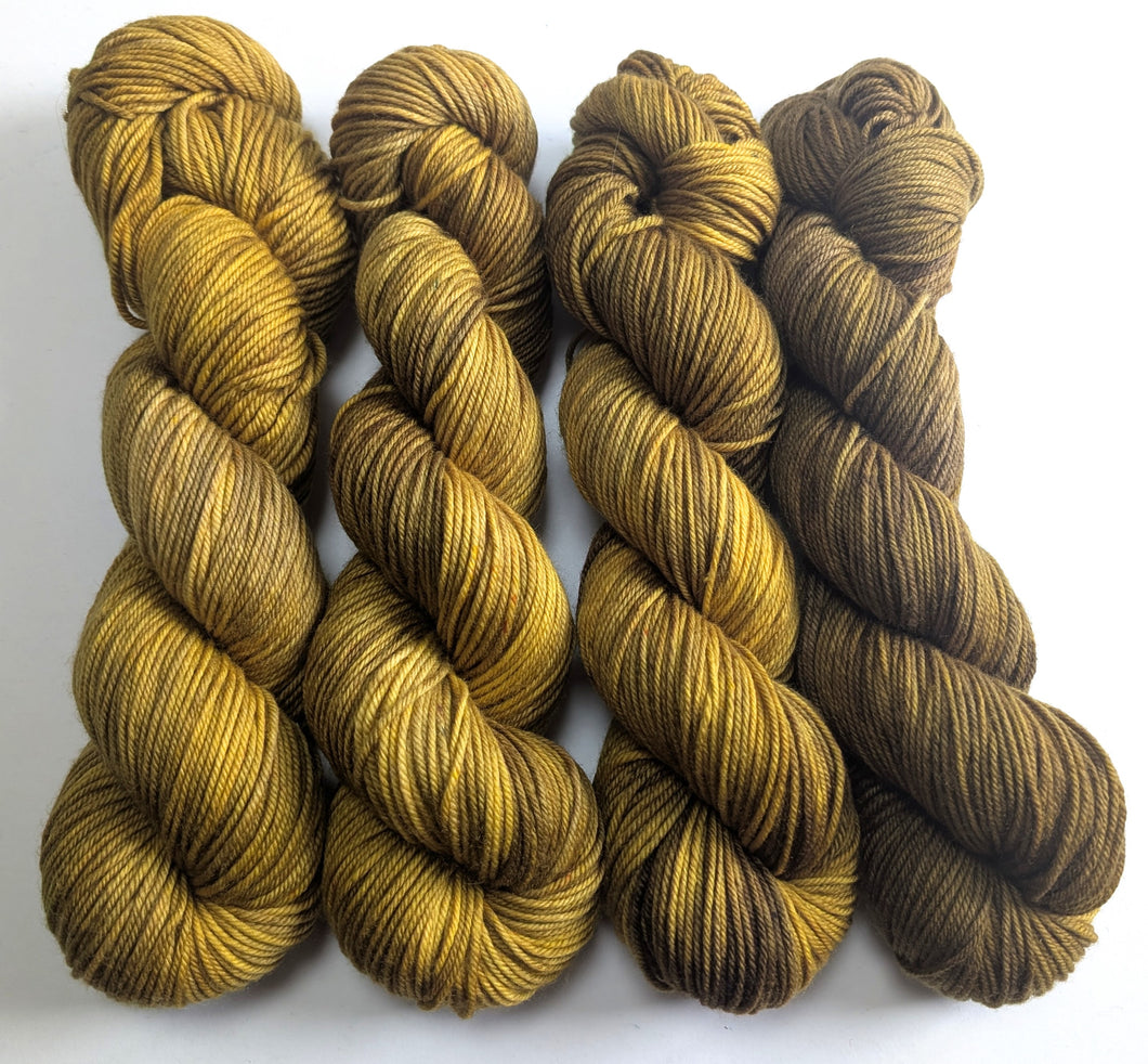 Four skeins of yellow and brown yarn on a white background