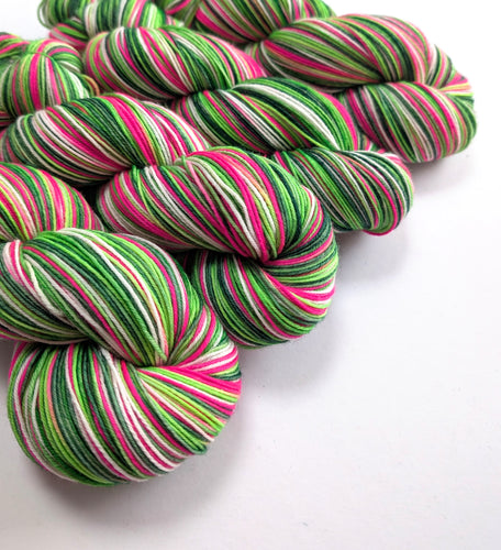 Skeins of yarn in pink, greens and white.
