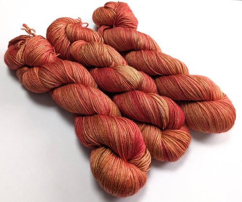Bunch of red and orange yarn skeins on a white background
