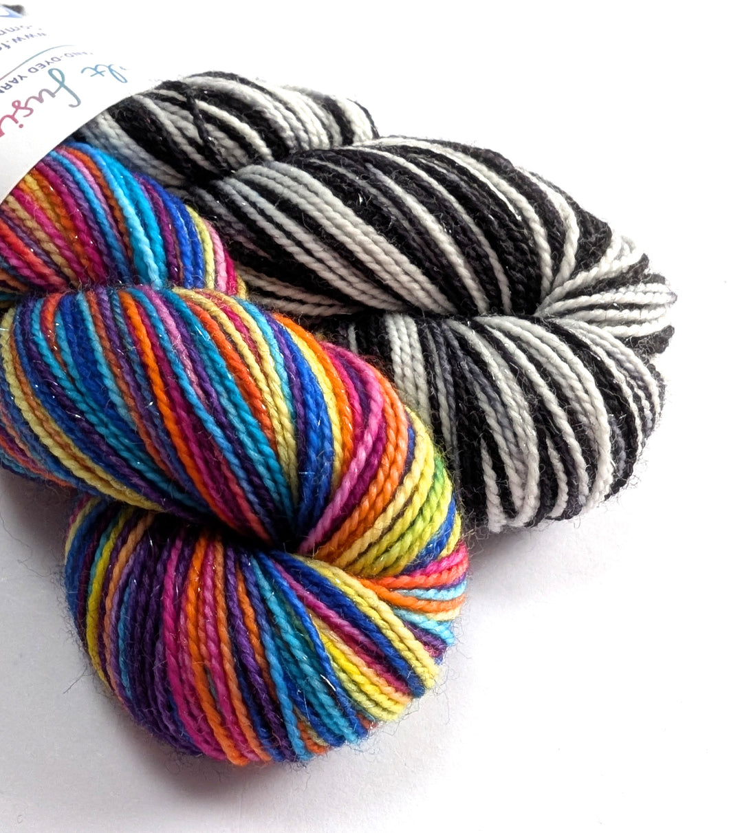 Two skeins of yarn, one multicolored and one black and white striped, on a white background.