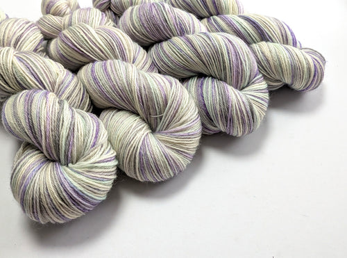Purple and white striped yarn skeins on a white background