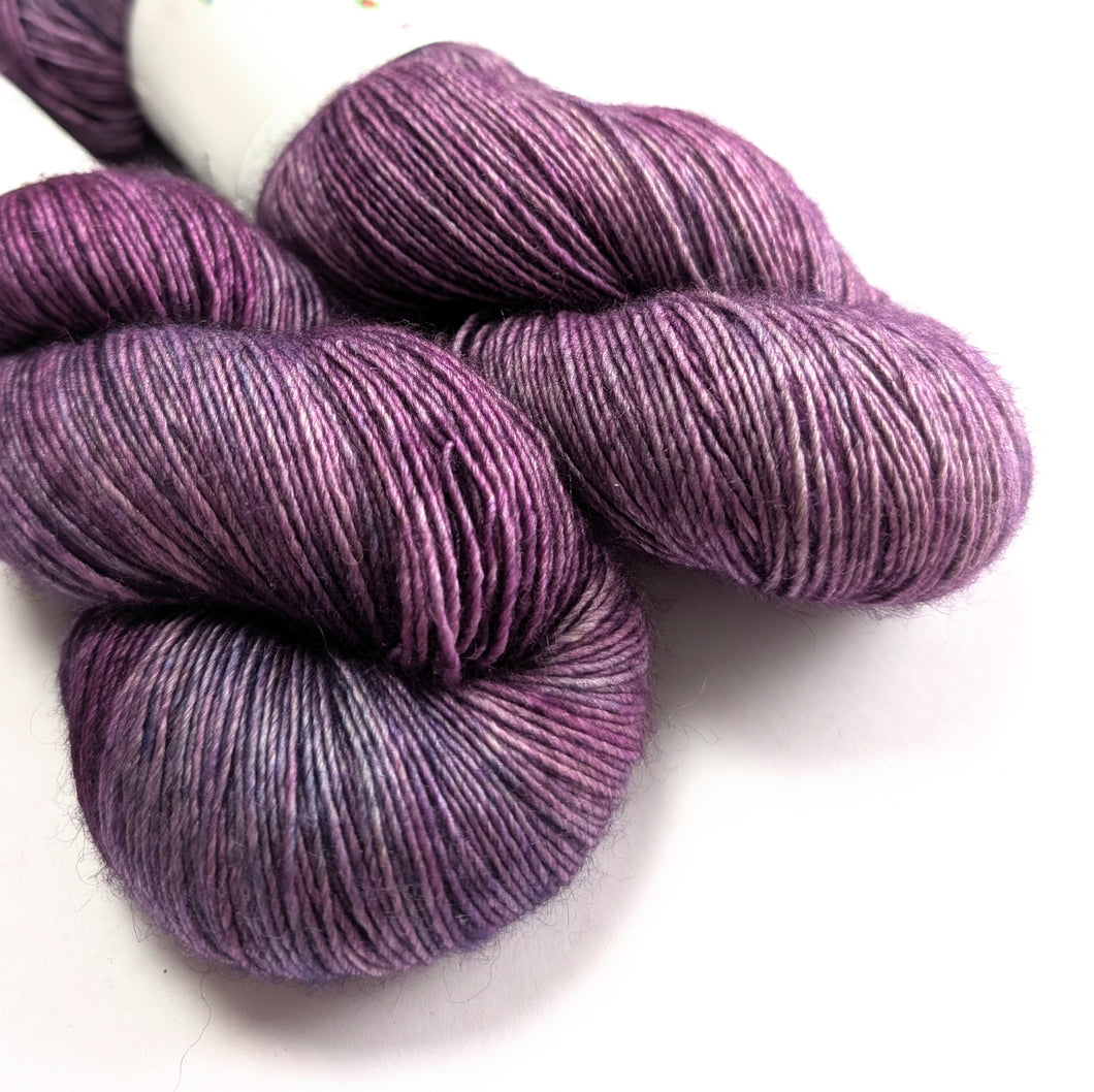 Two skeins of purple yarn on a white background.
