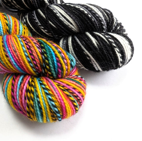 Two skeins of yarn, one multicolored and one black and white, on a white background.