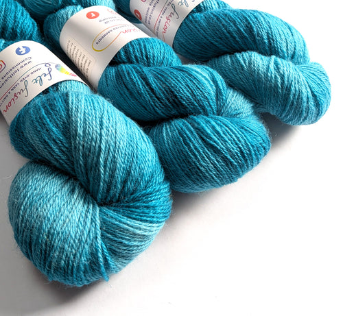 Three skeins of blue yarn with labels on a white background