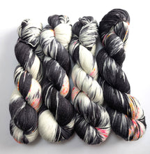 Load image into Gallery viewer, Four skeins of black, white, and gray yarn with multicolor accents on a white background
