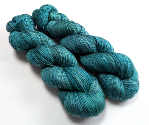 Two skeins of teal yarn on a white background