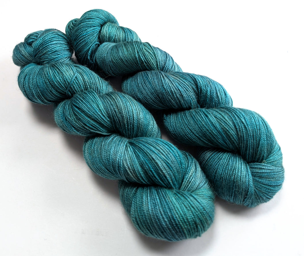 Two skeins of teal yarn on a white background