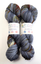 Load image into Gallery viewer, Two skeins of multicolored yarn with visible branding on a white background
