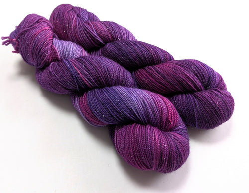 Two skeins of purple yarn on a white background
