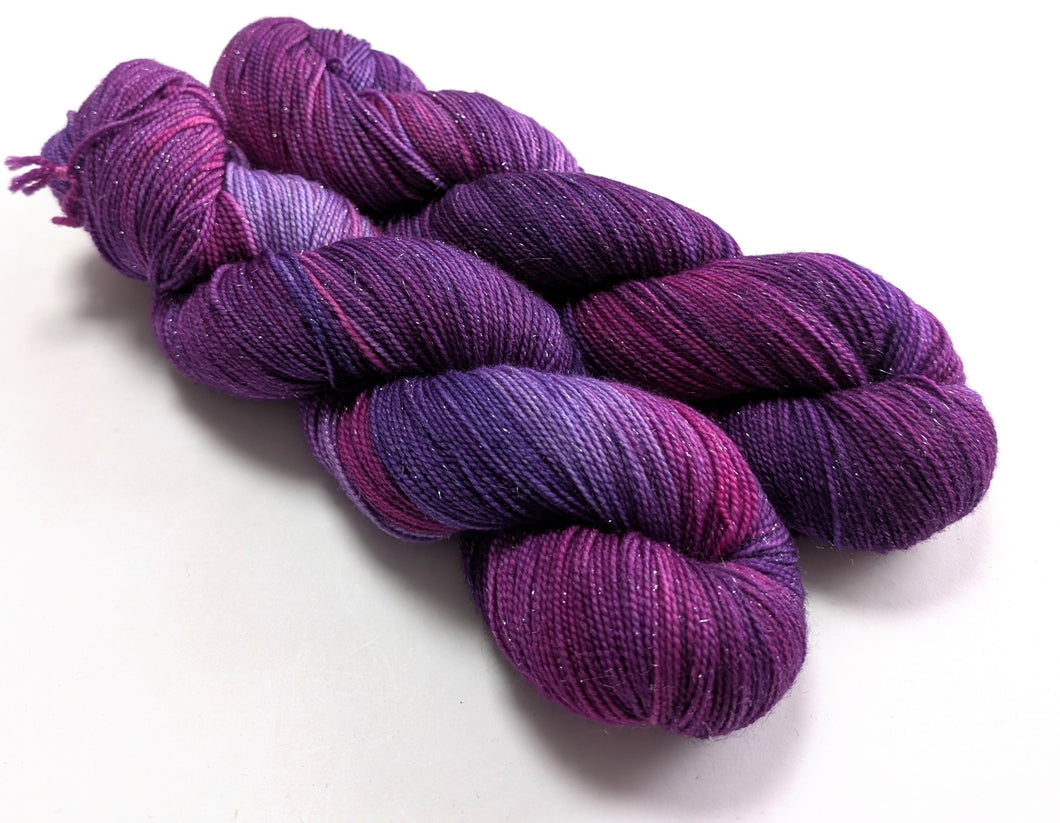 Two skeins of purple yarn on a white background