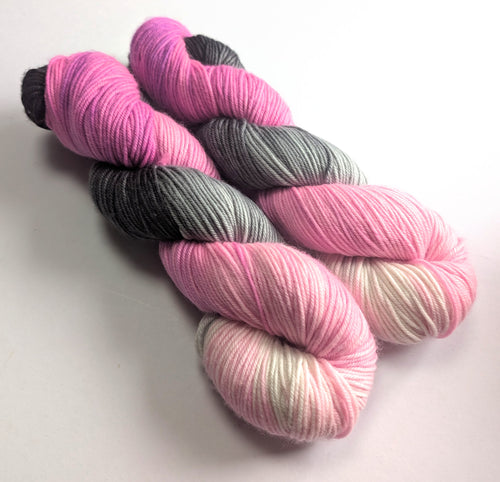 Two skeins of pink, gray, and multicolored yarn on a white background