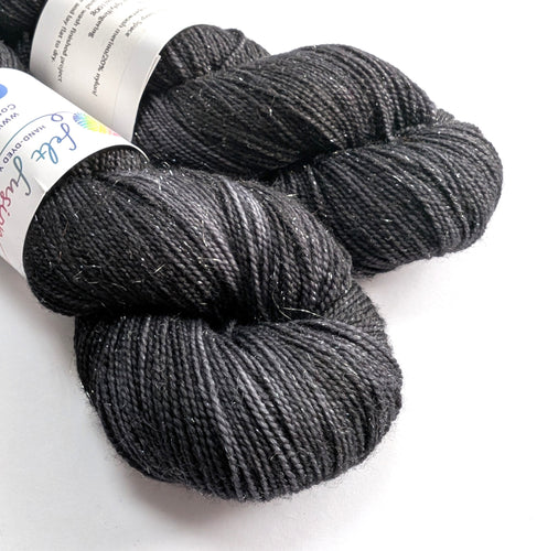 Two skeins of dark gray yarn with labels on a white background