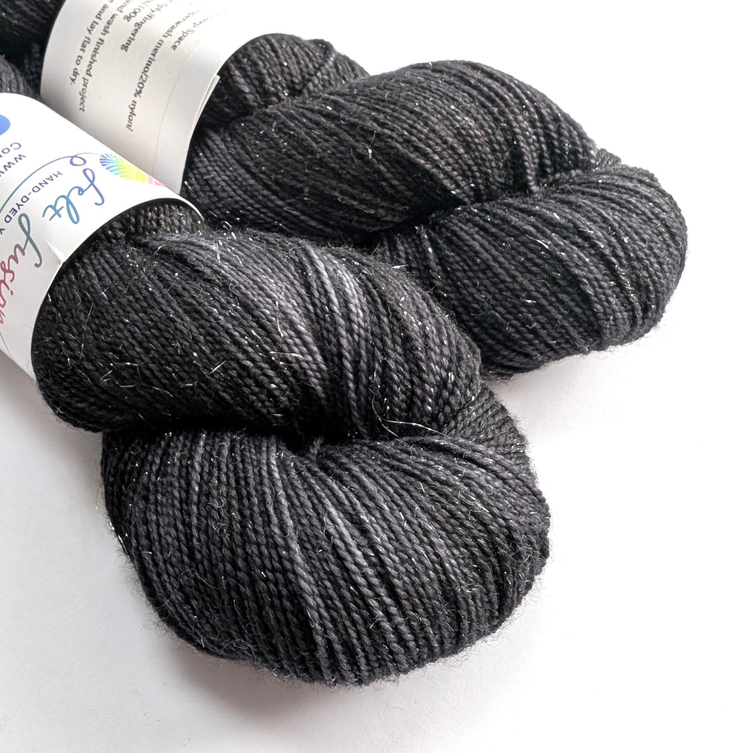 Two skeins of dark gray yarn with labels on a white background