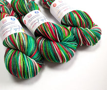 Load image into Gallery viewer, Three skeins of variegated yarn with white paper labels, featuring stripes of green, red, and white, arranged on a plain white background.
