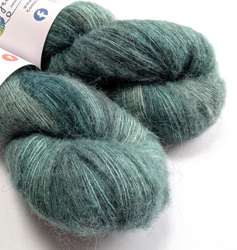 Two skeins of dark green yarn on a white background
