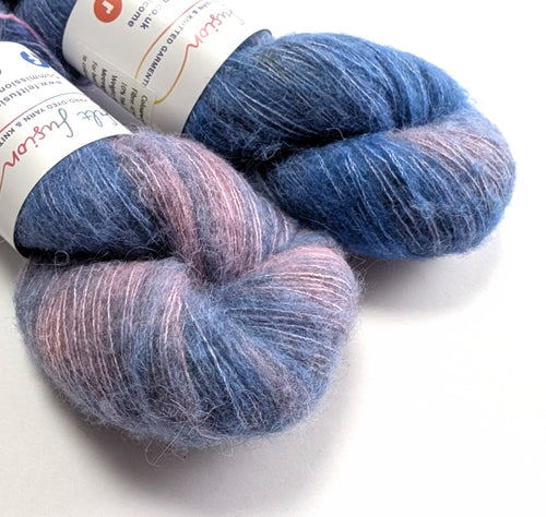 Two skeins of blue and pink yarn with labels on a white background