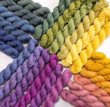 Load image into Gallery viewer, Colorful yarn skeins arranged in a gradient on a white background
