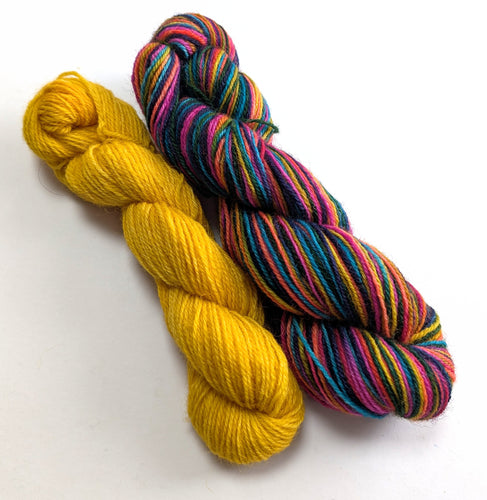 Two skeins of yarn, one yellow and one multicolored, on a white background