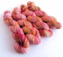 Load image into Gallery viewer, 4 twisted skeins of yarn dyed in pink, with pink and gold and olive green splashes, on a white background.
