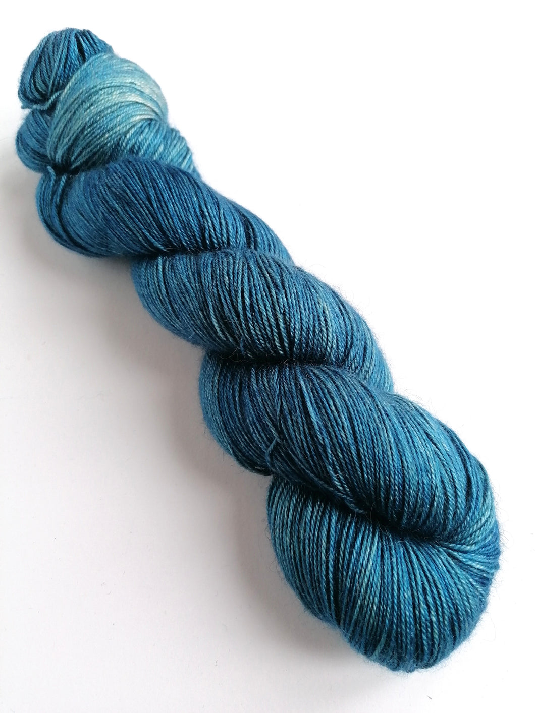 Mid blue twsted skein of yarn on a white background.