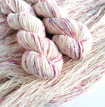 Load image into Gallery viewer, 2 twist skeins of natural yarn, with pink, red and purple speckles, laying on opened out skeins.
