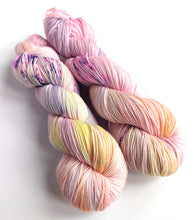Load image into Gallery viewer, Two skeins of yarn, dyed in pastel pinks, yellows and purple, with purple speckles.
