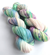 Load image into Gallery viewer, Two skeins dyed in gentle blues, pinks, greens and white, with purple speckles. On a white background.
